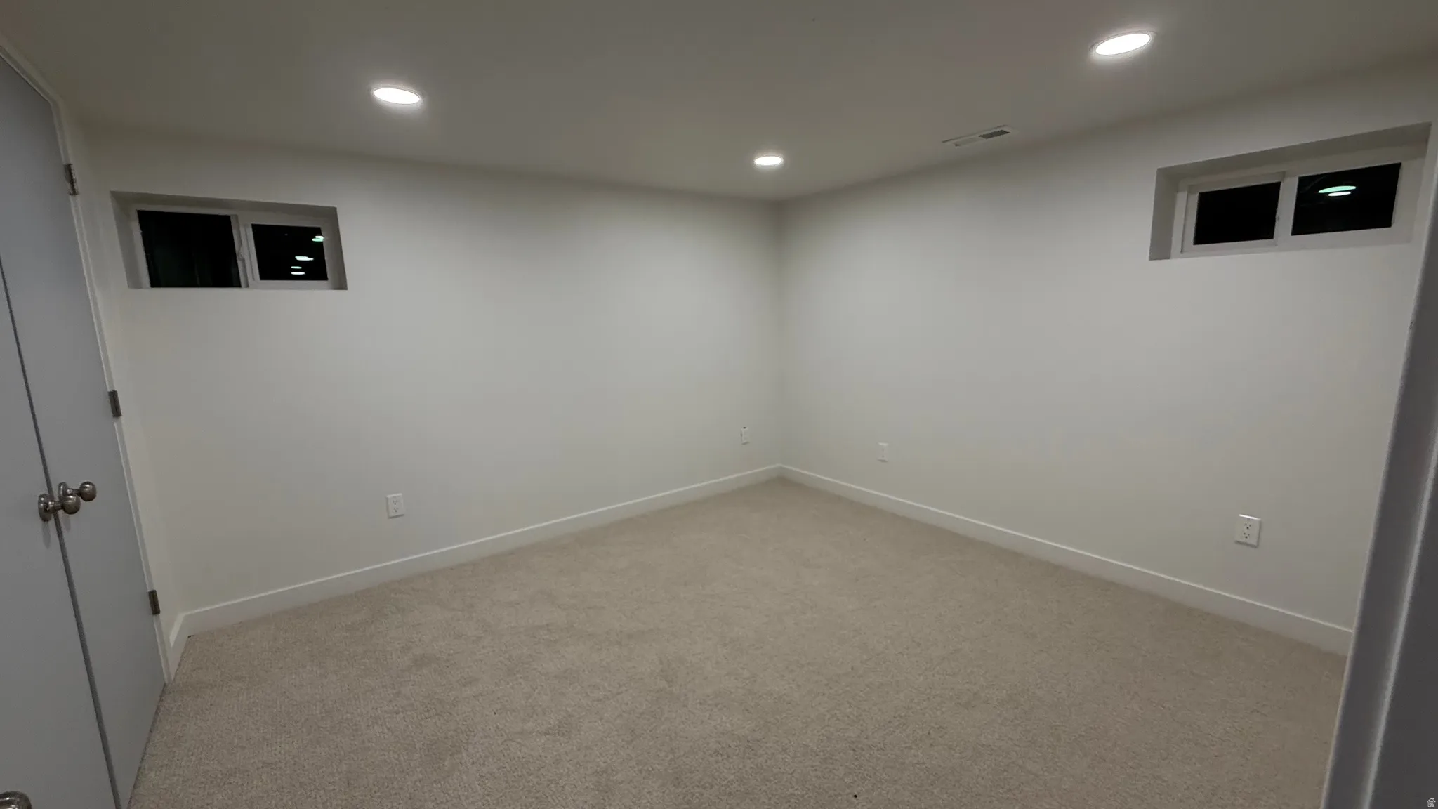 Recessed lighting, light-colored carpeting, white walls, and built-in windows