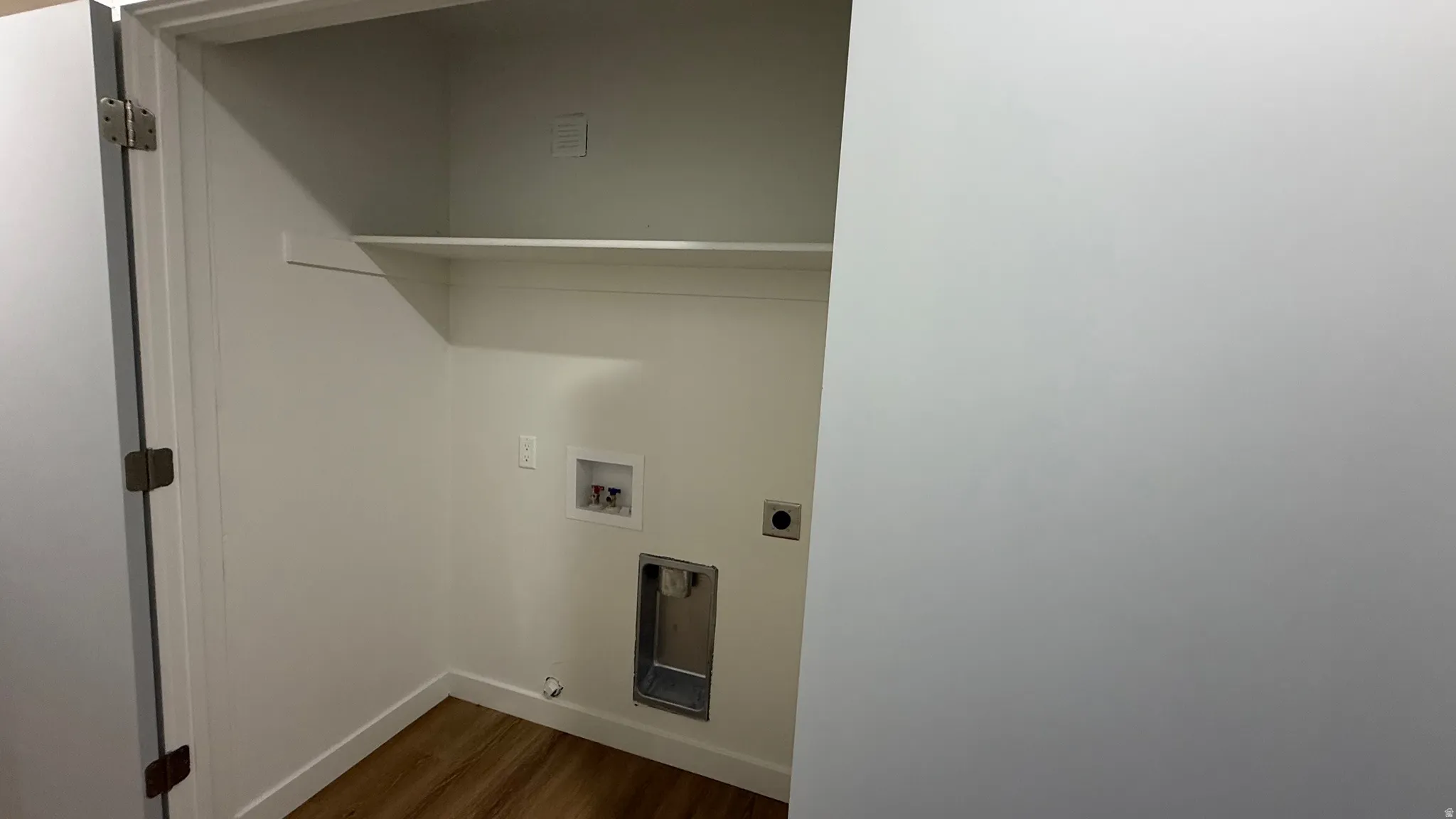Dedicated closet space featuring built-in shelving, wood-finish flooring, and convenient electrical outlets for added functionality and storage solutions