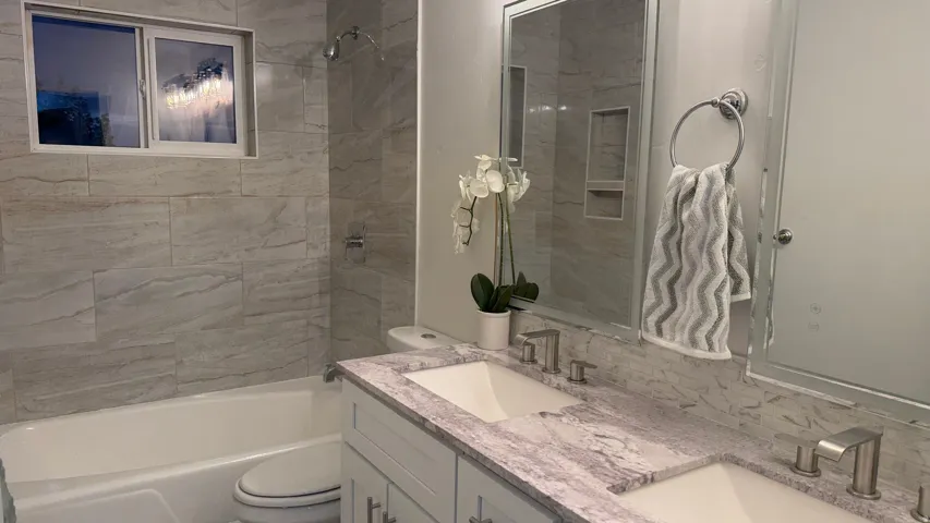 Spa-inspired bathroom featuring a marble-look quartz countertop, dual vanity with brushed nickel fixtures, and large framed mirror