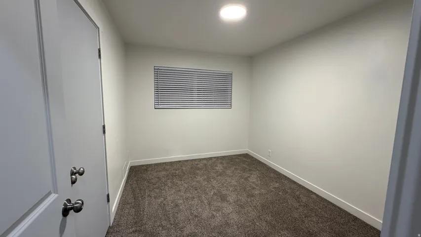 Recessed ceiling light, neutral wall paint, window with blinds, and textured carpet flooring