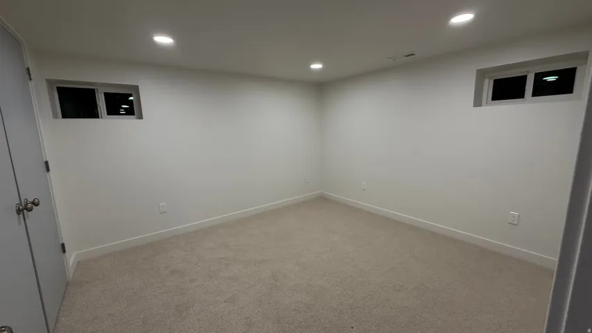 Recessed lighting, light-colored carpeting, white walls, and built-in windows