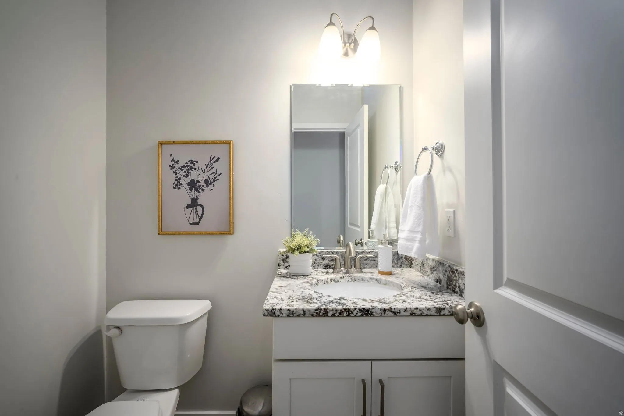 Elegant half bath bathroom featuring a granite-topped vanity.