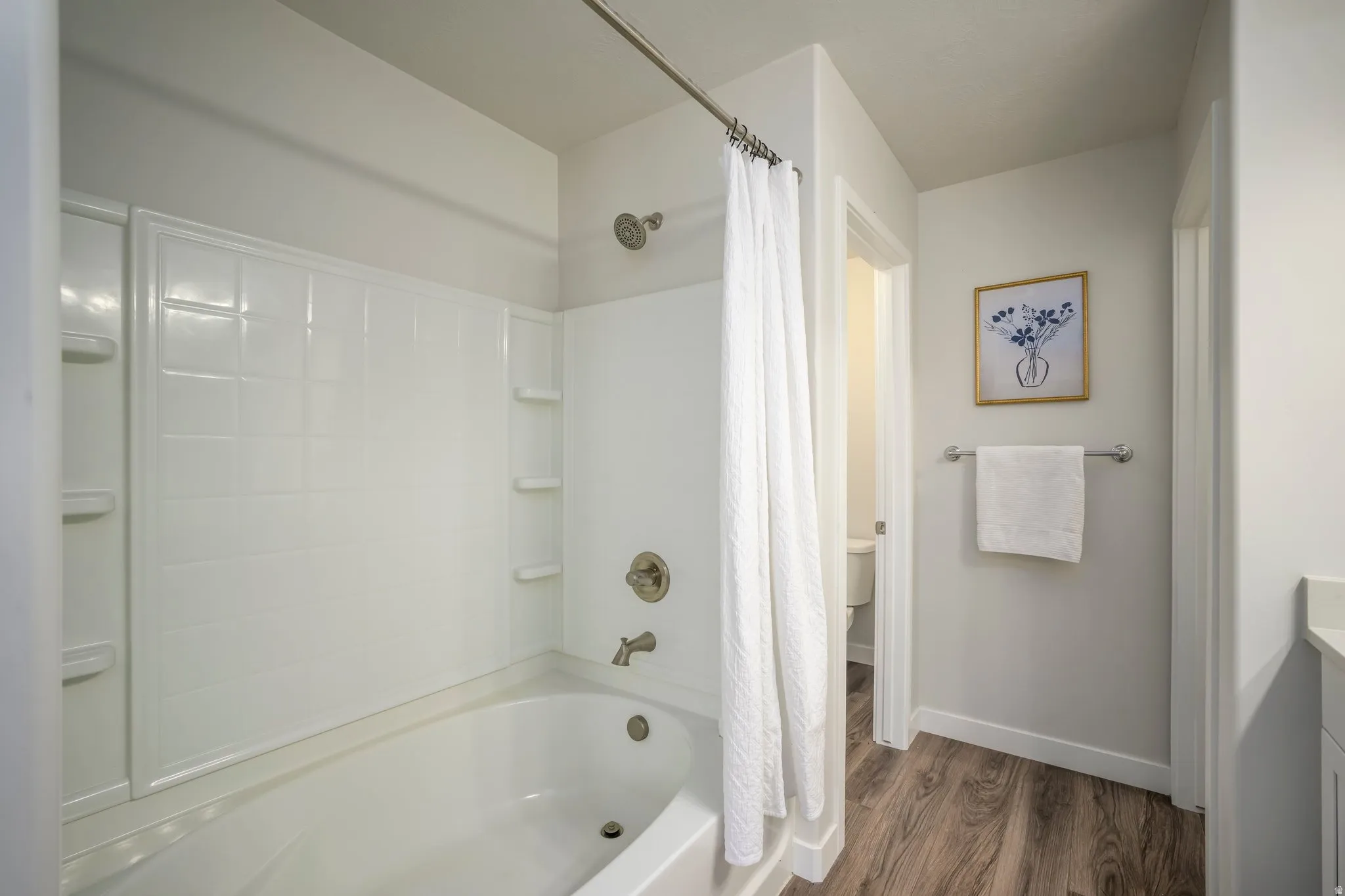 Primary Suite Spa-inspired bathroom featuring a combined tub and shower enclosure with seamless white acrylic surround, chrome fixtures, and a curved shower rod