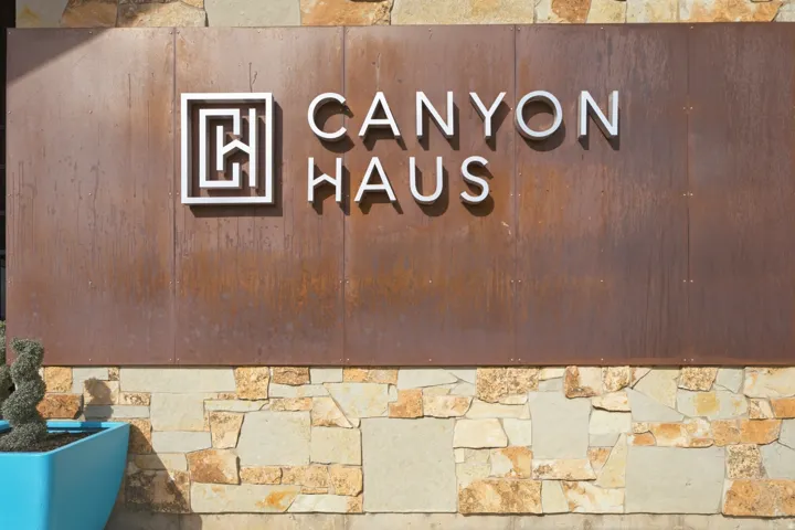 Exterior wall featuring natural stone cladding and a metal panel with raised lettering