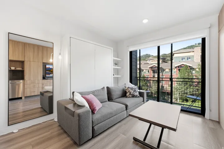 Sliding glass doors to a balcony, wood-finish flooring, built-in shelving, recessed lighting, and a neutral color palette