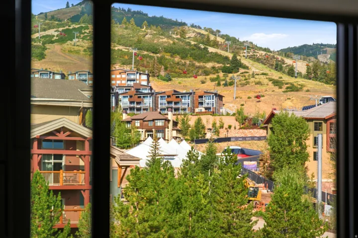 Mountainous terrain with ski lifts and distant buildings visible through a window frame
