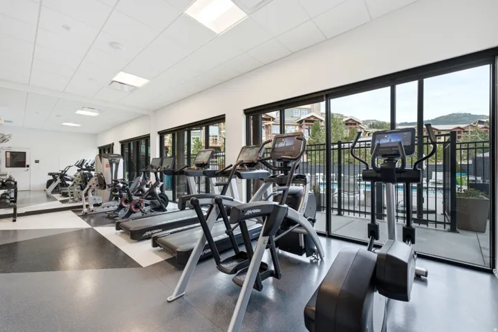 Fitness center featuring a mirrored wall, recessed lighting, and expansive glass doors opening to an outdoor patio with a metal railing