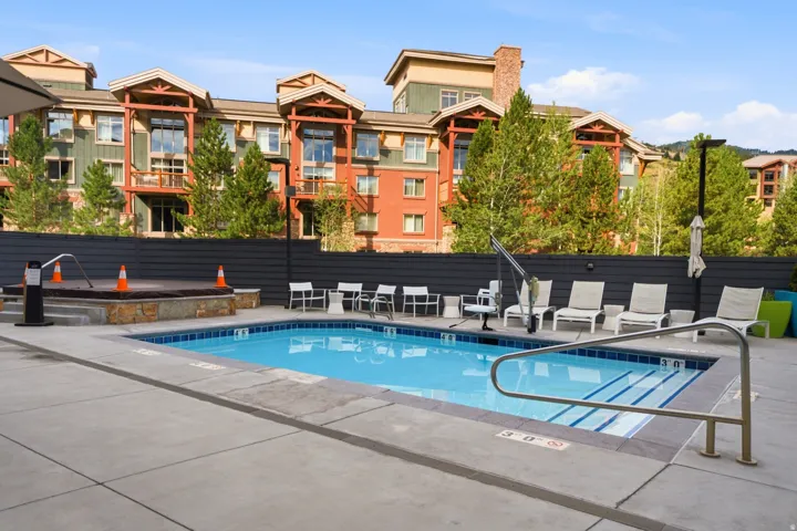 Outdoor swimming pool with integrated steps, adjacent hot tub with stone surround, and surrounding hardscaping