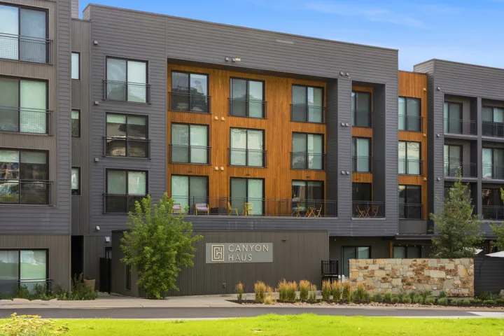Modern multi-story building featuring wood-paneled and gray siding accents
