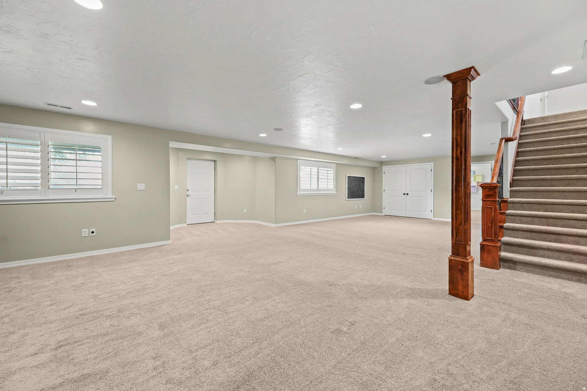 Spacious room featuring neutral carpeting, recessed lighting, and white plantation shutters