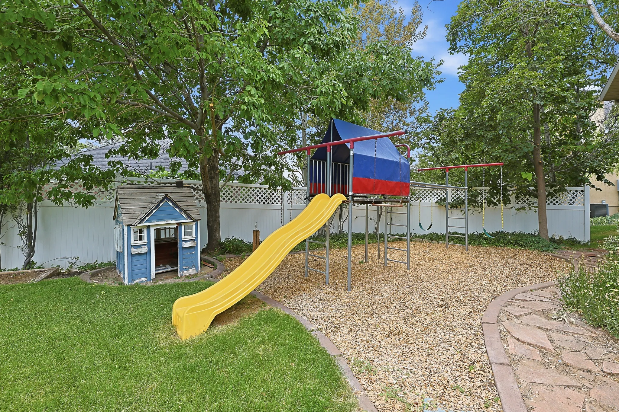 Expansive backyard featuring a manicured lawn, established trees, and a flagstone pathway