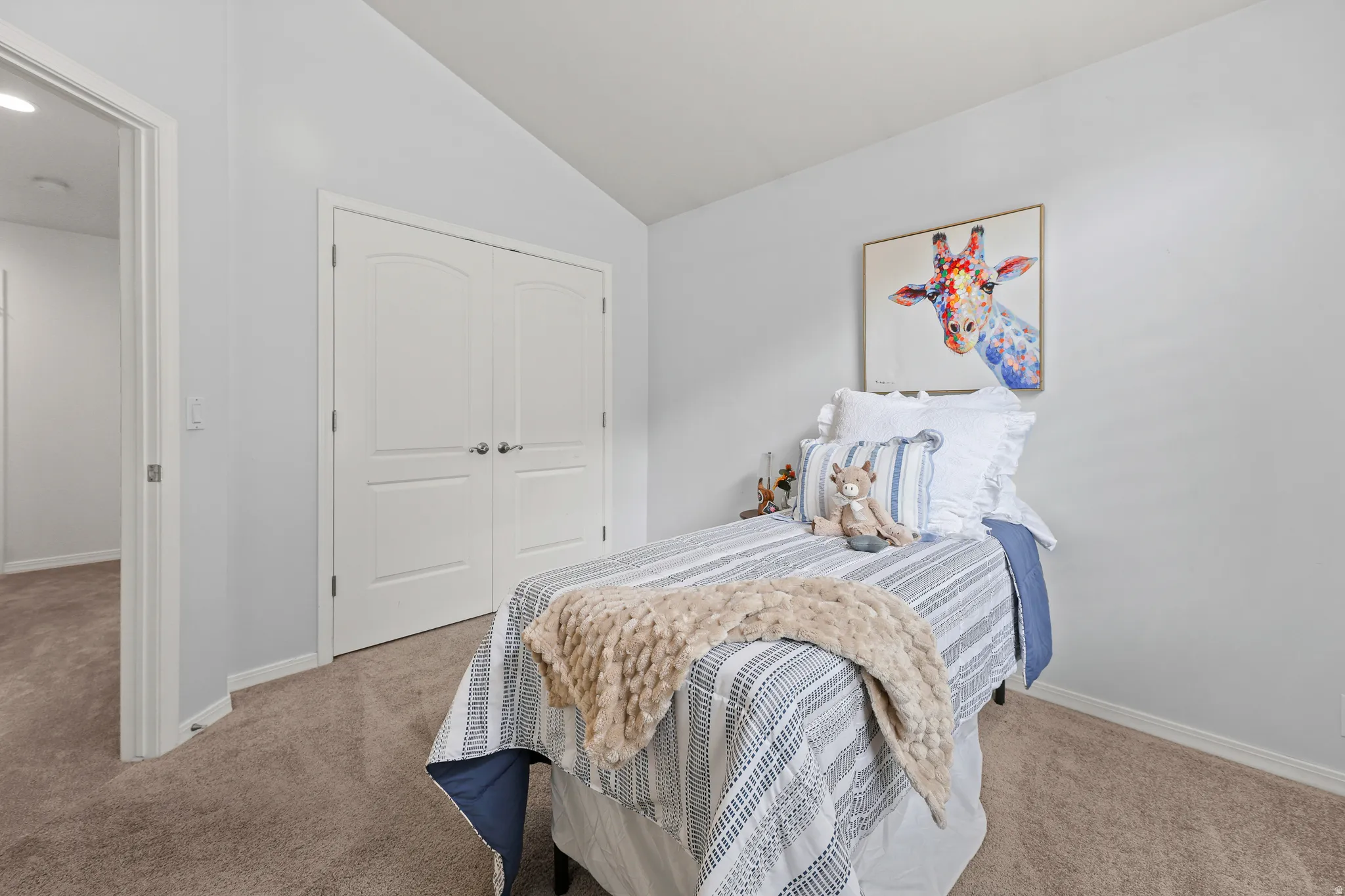 Carpeted room featuring a vaulted ceiling, white walls, and a double-door closet with arched paneling