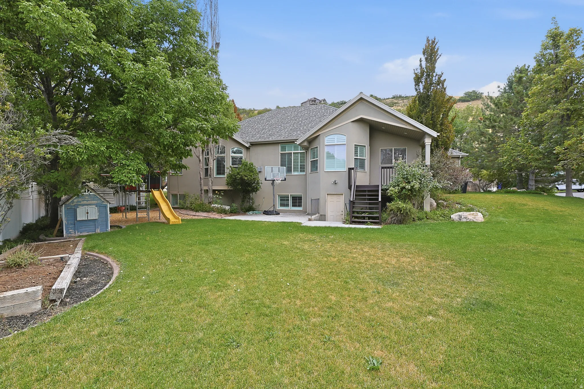Expansive lawn with mature trees and raised garden beds