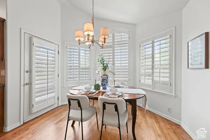 Hardwood flooring with a semicircular dining area, multiple windows with white plantation shutters, and a chandelier with fabric shades