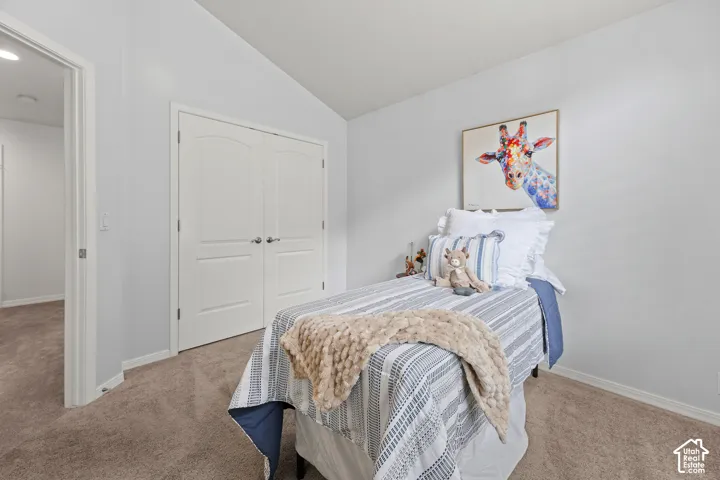 Carpeted room featuring a vaulted ceiling, white walls, and a double-door closet with arched paneling