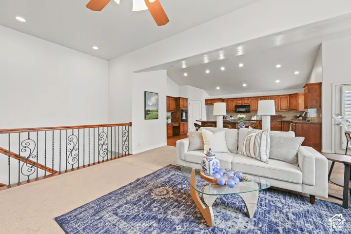 Open-concept living space with vaulted ceilings, recessed lighting, and a wood-finish railing with decorative metal spindles