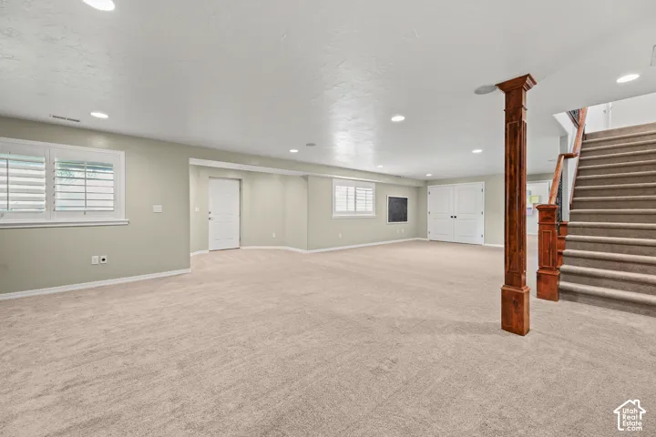 Spacious room featuring neutral carpeting, recessed lighting, and white plantation shutters