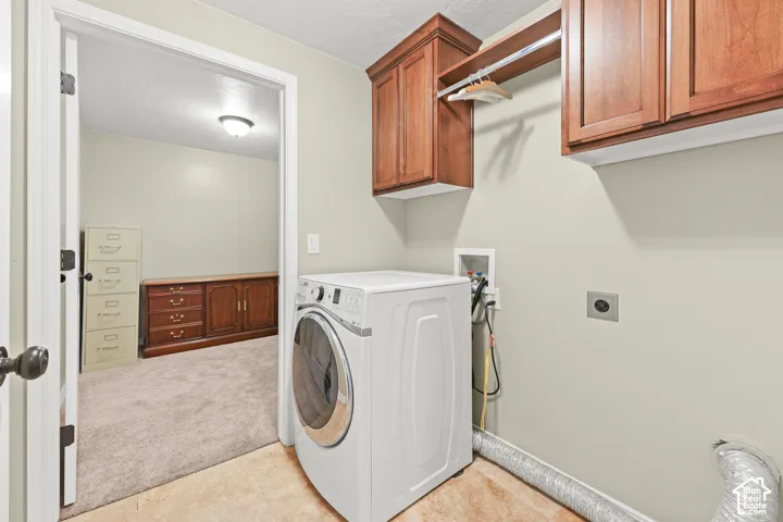 Laundry area featuring wood cabinetry, integrated hanging rod, and tile flooring