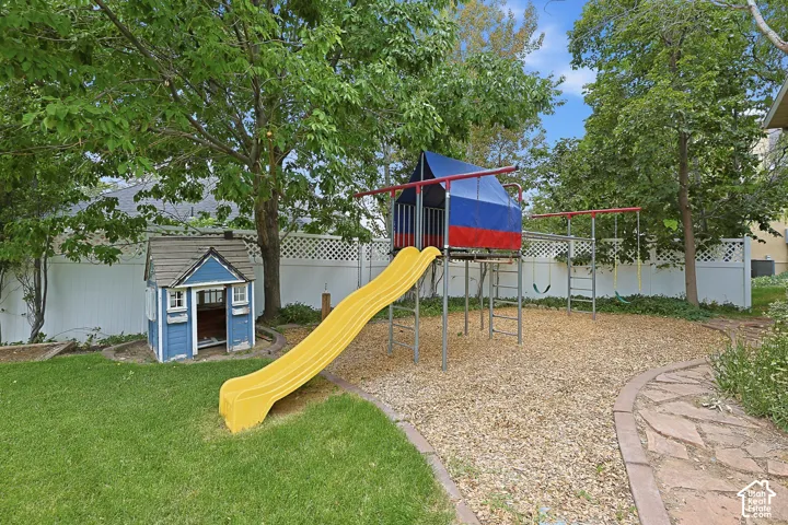 Expansive backyard featuring a manicured lawn, established trees, and a flagstone pathway