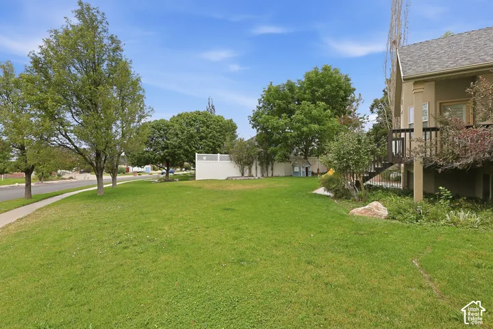 Expansive grassy yard with mature trees, a private deck, and a white fence