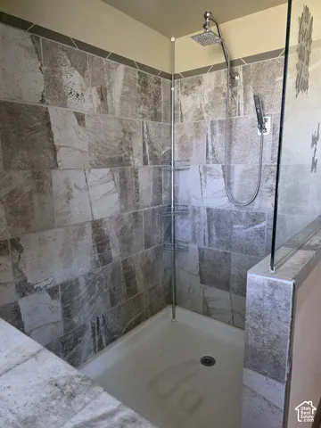 Tiled shower enclosure featuring a fixed rain shower head and a handheld shower