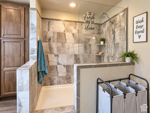 Walk-in shower with tiled walls, integrated shelving, and a glass partition