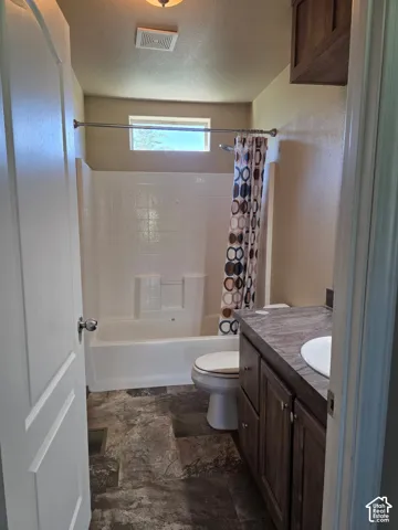 Bathroom featuring a full-size bathtub with white tile surround, a single vanity with wood-finish cabinetry, a white basin sink, and wood-finish flooring