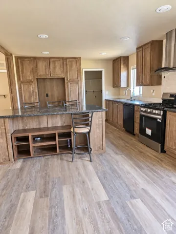 Kitchen featuring wood-finish flooring, recessed lighting, wood cabinetry, stone countertops, and stainless steel appliances