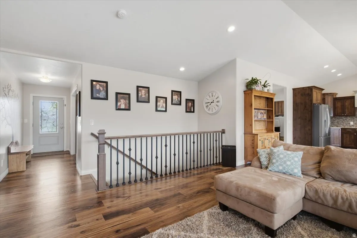 Hardwood-finish flooring throughout, recessed ceiling lighting, and a kitchen featuring dark wood cabinetry with a tile backsplash and stainless steel appliances