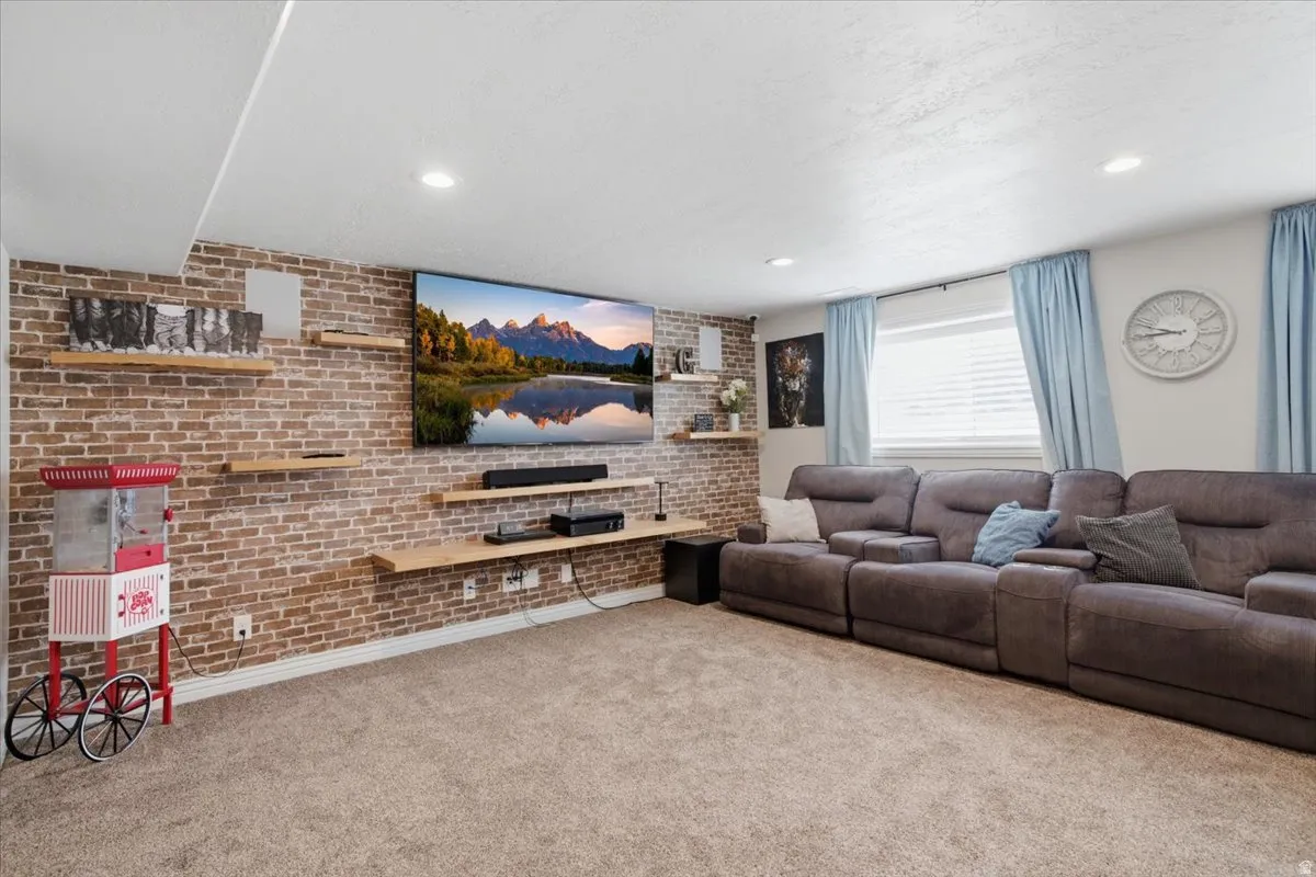 Exposed brick accent wall, recessed lighting, and light-colored carpeting