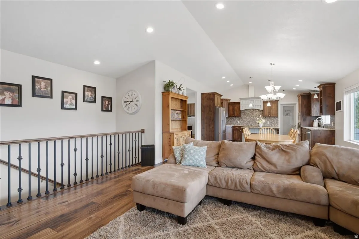 Vaulted ceilings with recessed lighting, wood-finish flooring, staircase with wrought iron balusters, built-in kitchen cabinetry, and a mosaic tile backsplash