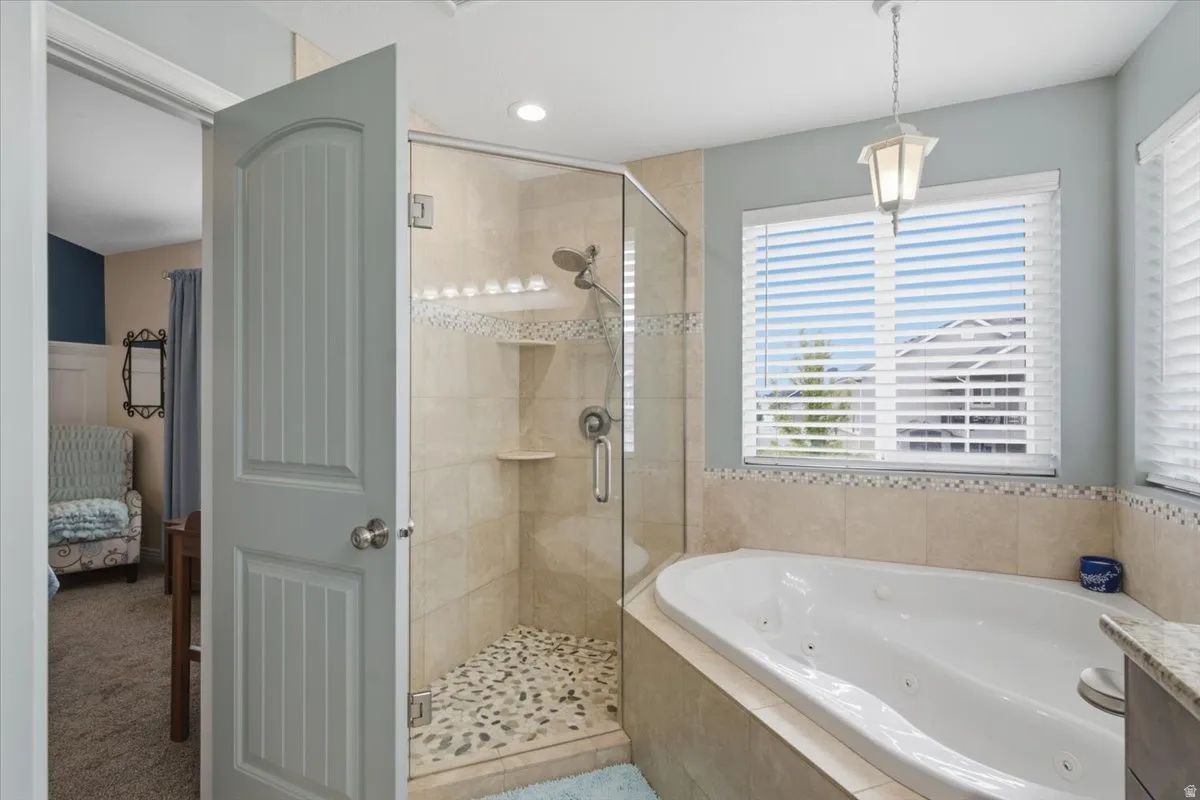Spa-inspired primary bathroom featuring a frameless glass-enclosed walk-in shower with pebble-stone flooring and built-in shelving, paired with a separate soaking tub