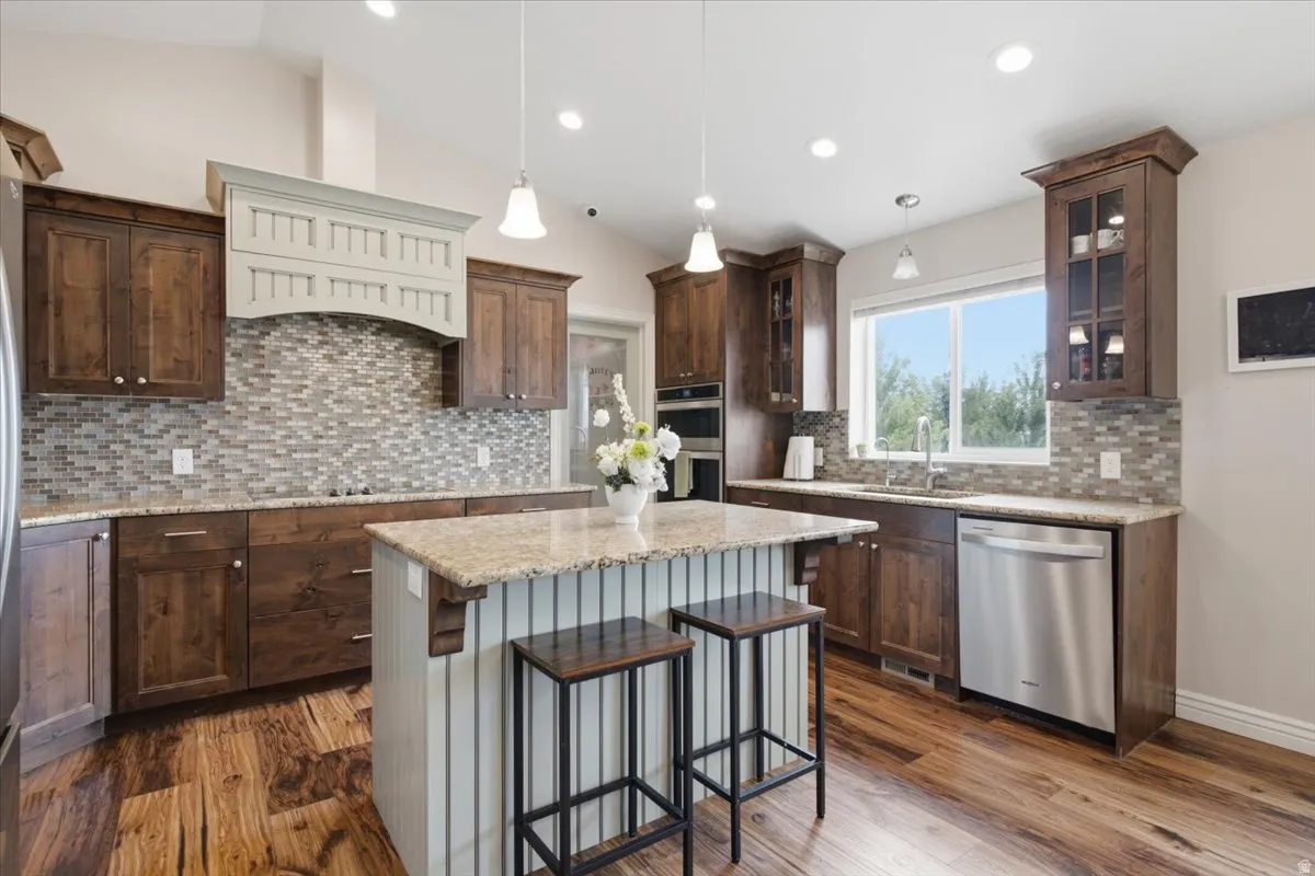 Contemporary kitchen featuring rich wood cabinetry, a white subway tile hood surround, mosaic tile backsplash, and stainless steel appliances