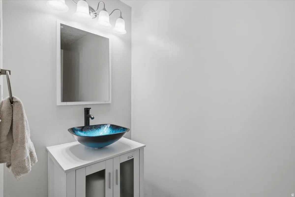 Modern bathroom vanity featuring a white quartz countertop, blue glass vessel sink, and matte black faucet