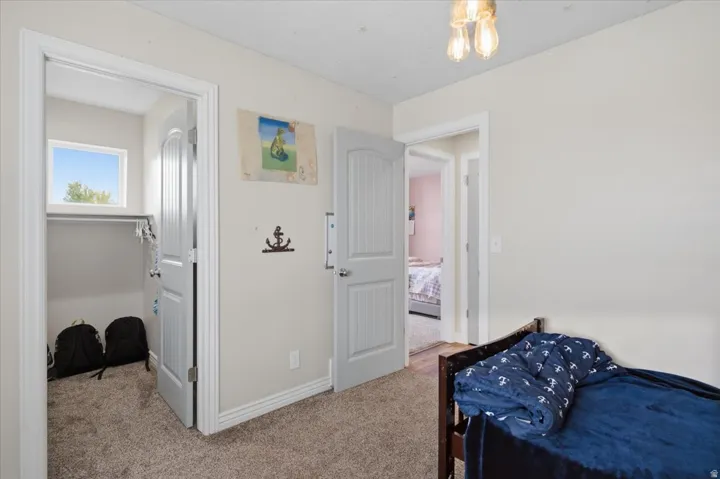 Bright secondary bedroom featuring carpeted flooring, a ceiling-mounted light fixture, and multiple closet spaces