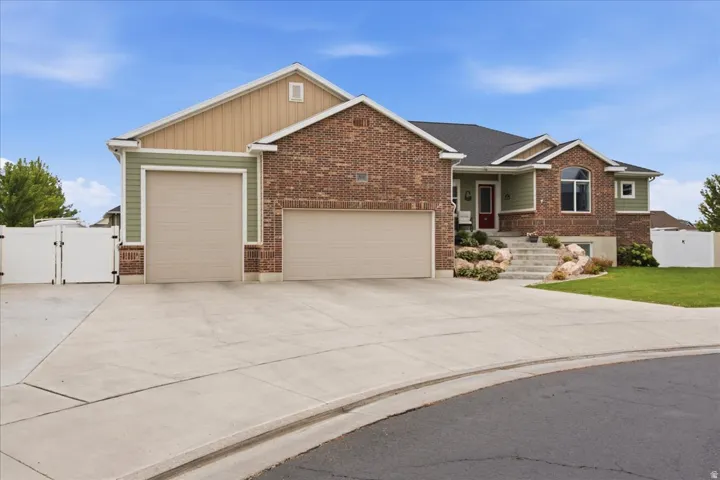 Brick and siding exterior with a dark shingle roof, featuring two garage doors and a paved driveway