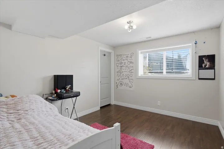 Bright secondary bedroom featuring wood-finish flooring, recessed ceiling lighting, and large windows with blinds providing natural light and privacy
