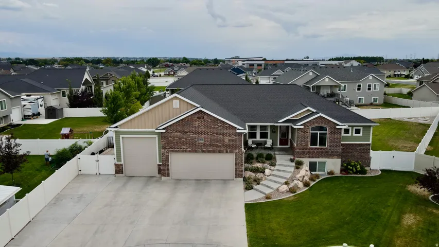 Brick Colonial home showcasing a multi-car garage with concrete driveway, manicured lawn, and stone entry steps