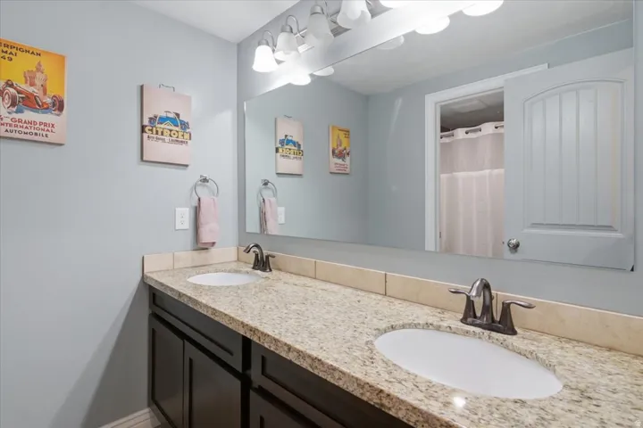 Dual-sink vanity with espresso cabinetry, granite-style countertop, and brushed nickel faucets