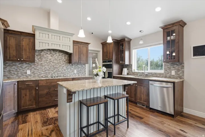 Contemporary kitchen featuring rich wood cabinetry, a white subway tile hood surround, mosaic tile backsplash, and stainless steel appliances