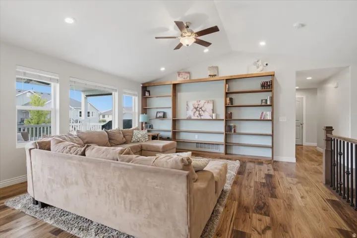 Bright open-concept living area featuring hardwood flooring, recessed lighting, and a ceiling fan with integrated light fixture