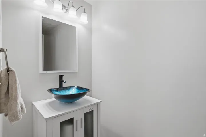 Modern bathroom vanity featuring a white quartz countertop, blue glass vessel sink, and matte black faucet