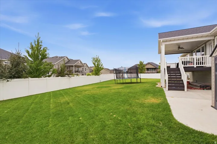 Expansive backyard featuring a manicured lawn, vinyl privacy fencing, and mature landscaping