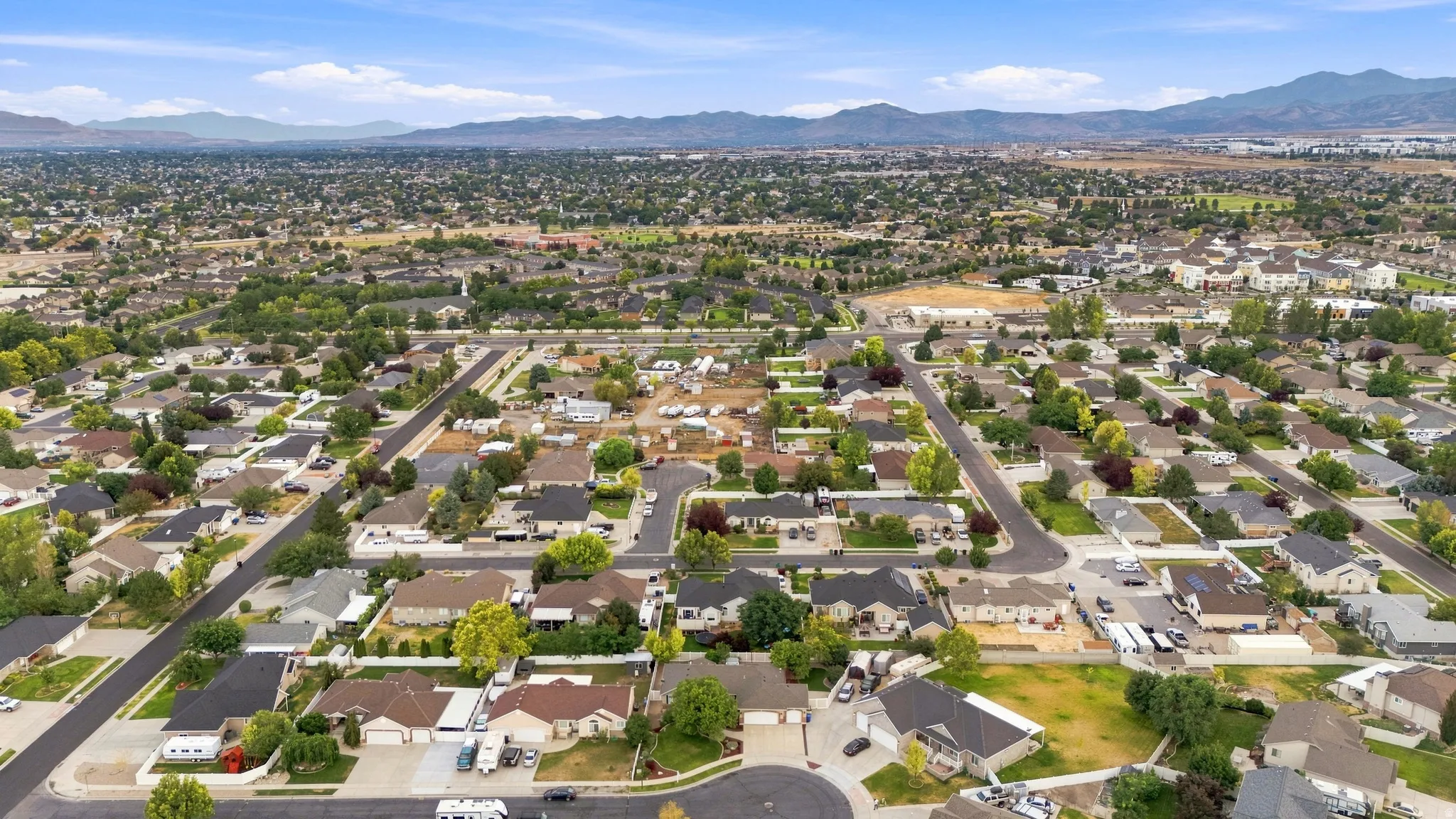 Residential neighborhood with mature trees, paved streets, and distant mountains