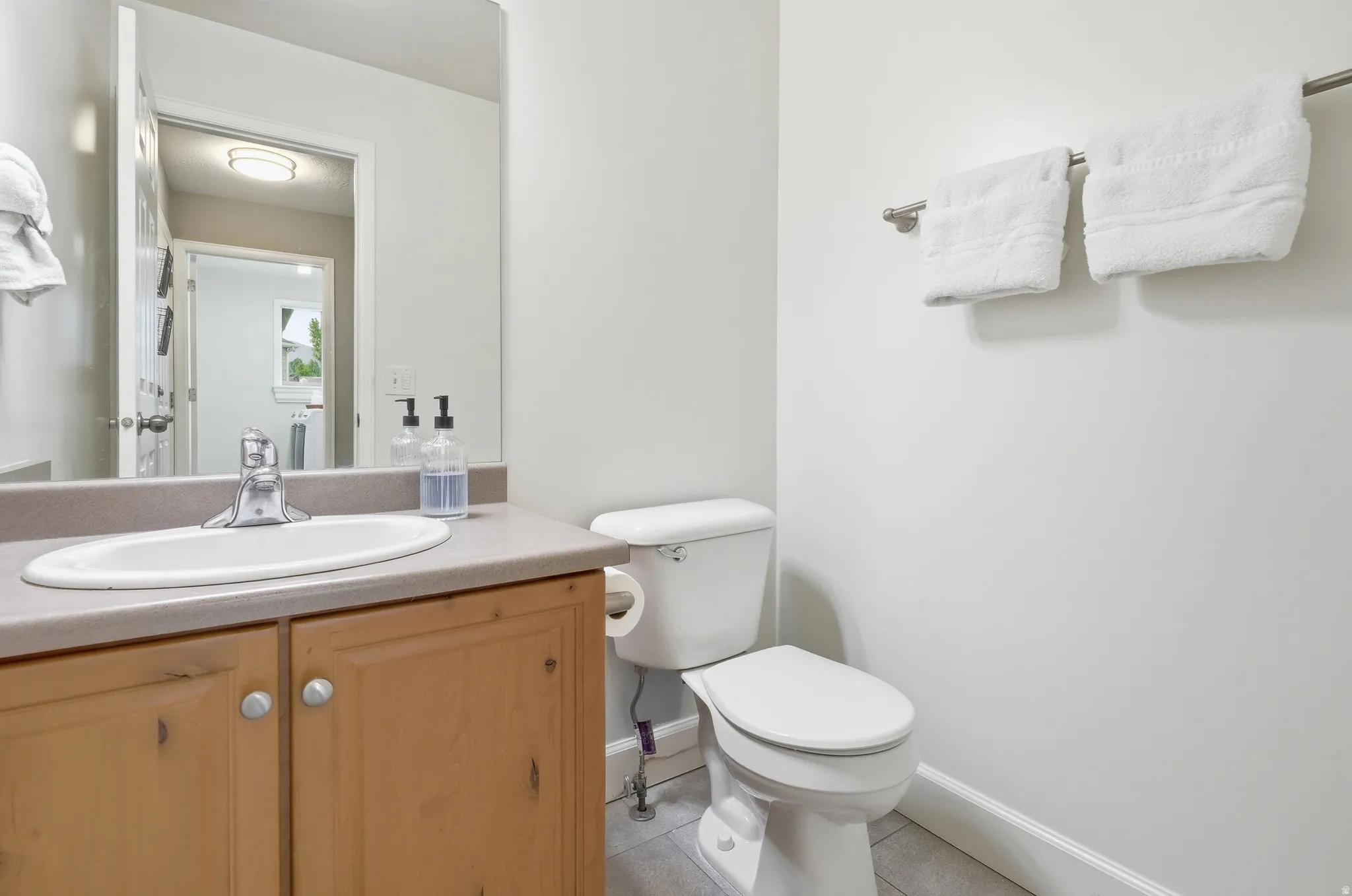 Vanity with wood-finish cabinetry, integrated sink, and chrome faucet