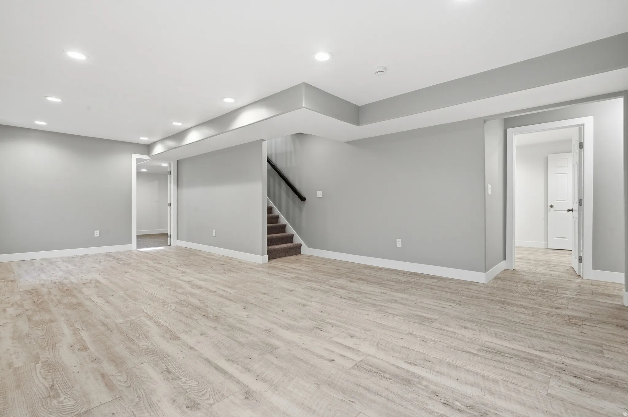 Spacious room with wood-finish flooring, recessed lighting, neutral wall tones, and white trim