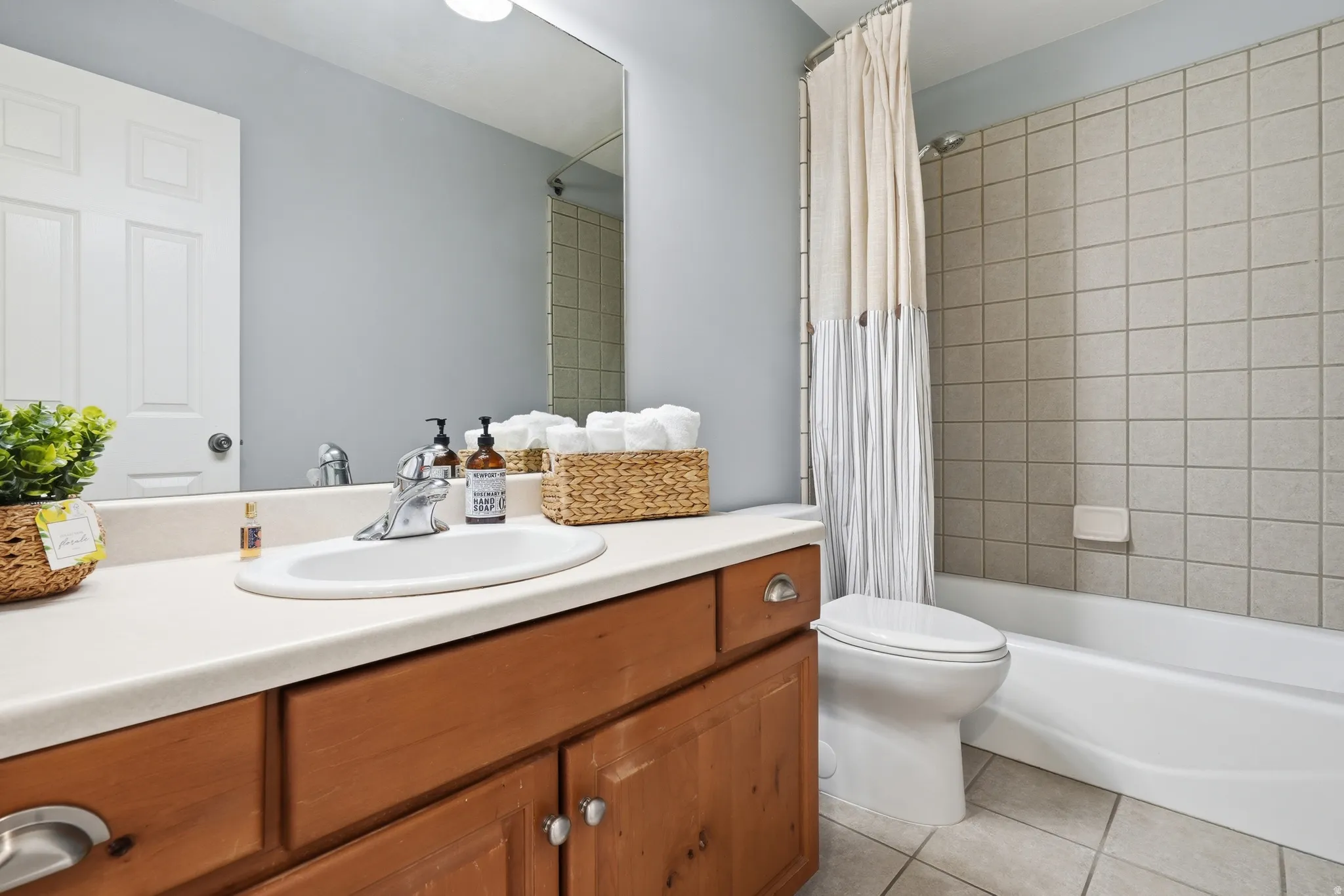 Spa-inspired bathroom featuring a wood-finish vanity with dual-sink configuration, white quartz countertop, and chrome faucetry