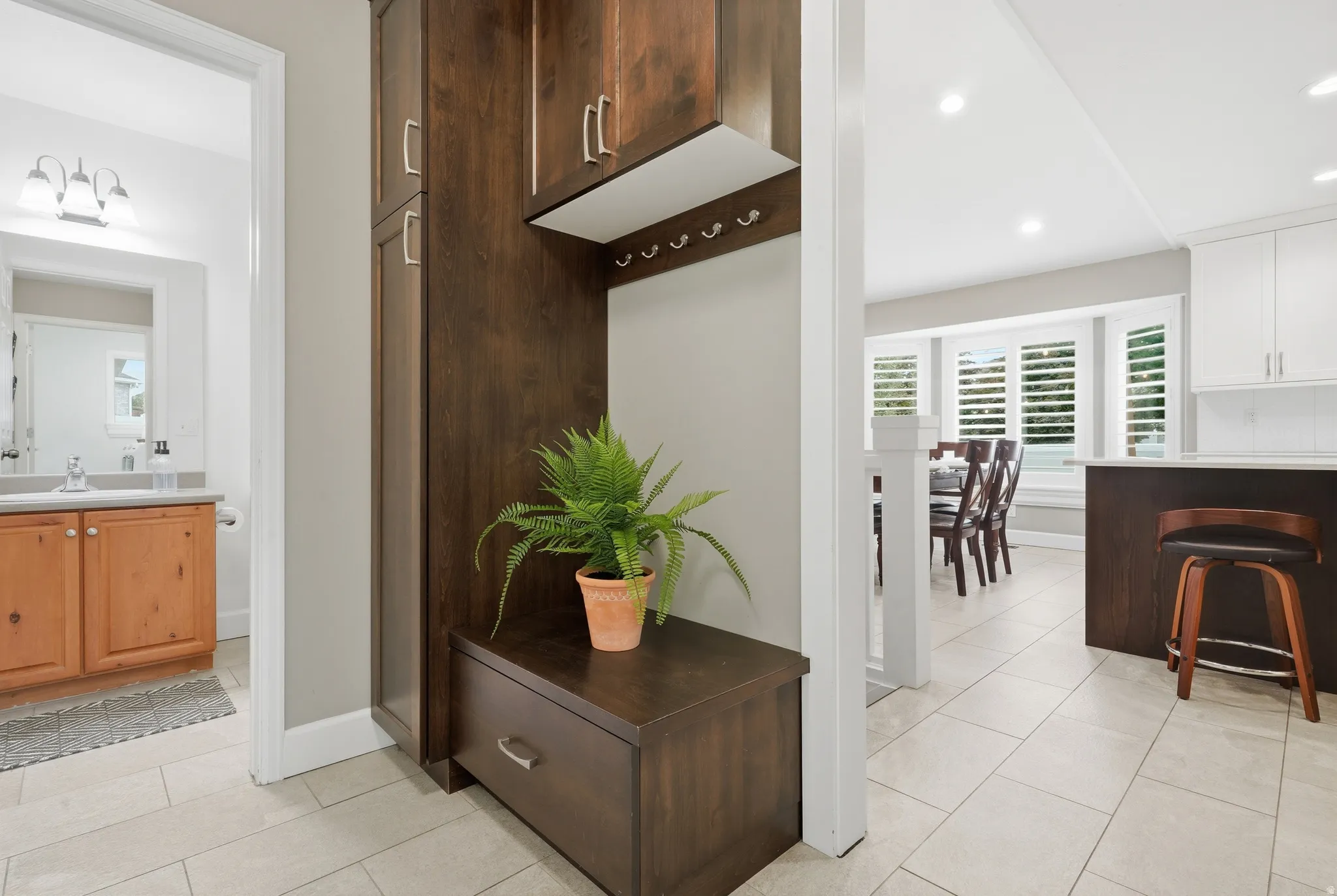 Built-in dark wood cabinetry with storage, light-toned tile flooring, recessed lighting, and white plantation shutters