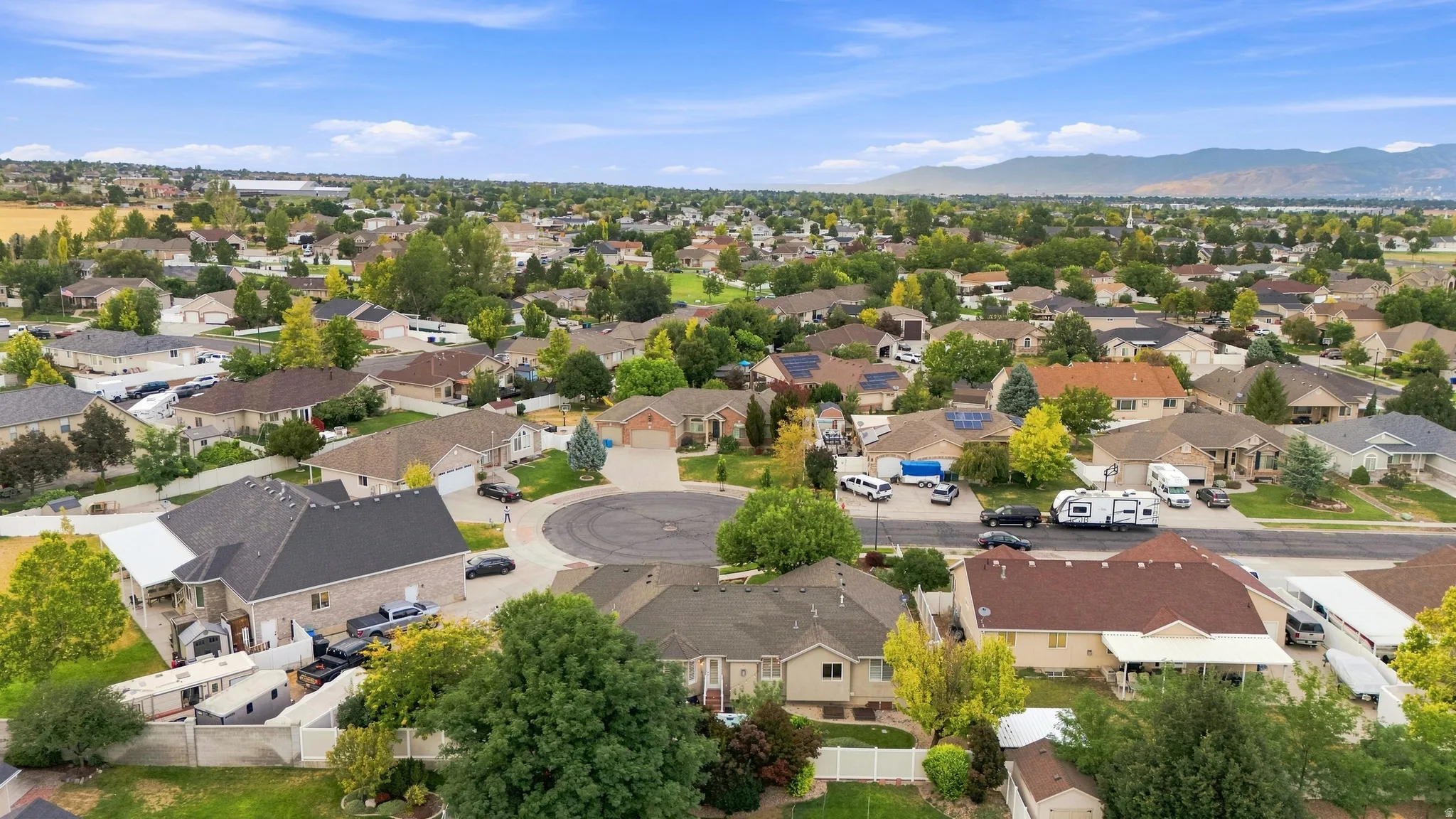 Residential neighborhood setting with mature trees and a distant mountain backdrop