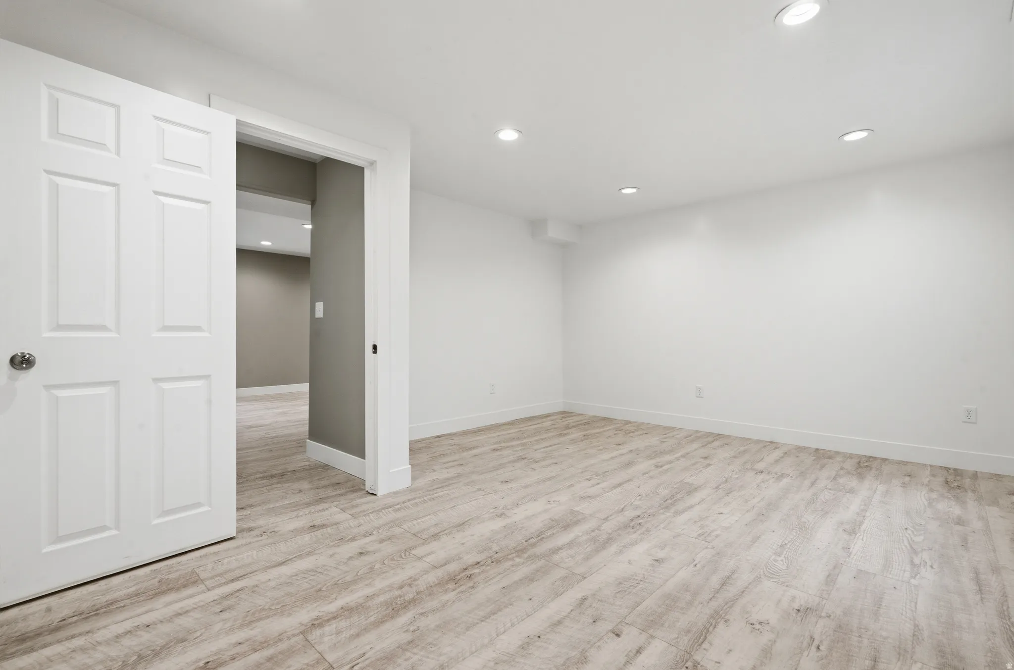 Recessed lighting illuminating the white walls and wood-finish flooring